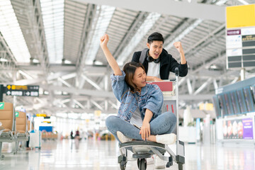 Happy smiling asian male and female waiting for flight and Check-in by mobile phone in terminal...