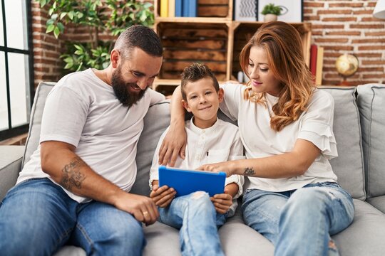 Family using touchpad hugging each other sitting on sofa at home