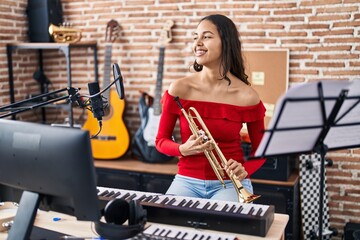 Fototapeta na wymiar Young african american woman musician playing trumpet at music studio