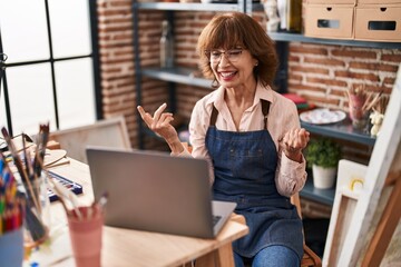 Middle age woman artist smiling confident having video call at art studio
