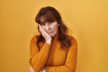 Middle age hispanic woman standing over yellow background thinking looking tired and bored with...