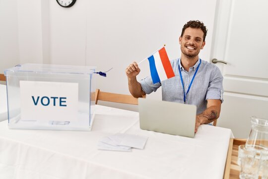 Young hispanic man smiling confident holding holland flag working at electoral college