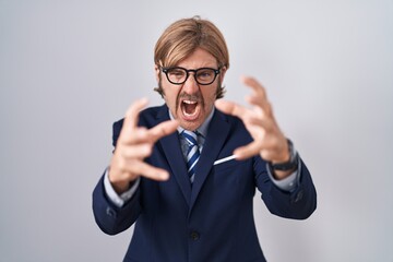 Caucasian man with mustache wearing business clothes shouting frustrated with rage, hands trying to strangle, yelling mad