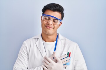 Hispanic man working as scientist smiling with hands on chest with closed eyes and grateful gesture on face. health concept.