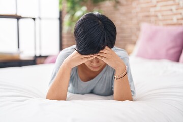 Middle age chinese woman stressed lying on bed at bedroom