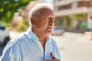 Senior grey-haired man standing suffering for heart attack at street