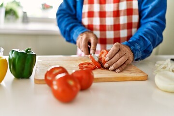 Senior man cutting tomato at kitchen