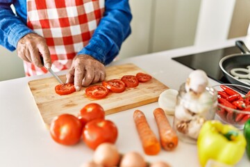 Senior man cutting tomato at kitchen