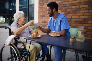 Caregiver having breakfast with his client at cafe.