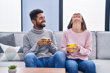 Man and woman couple sitting on sofa drinking coffee at home