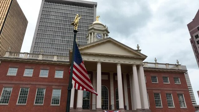 American flag at Old State House in downtown Hartford Connecticut. Gold building and skyscrapers surround aerial view.