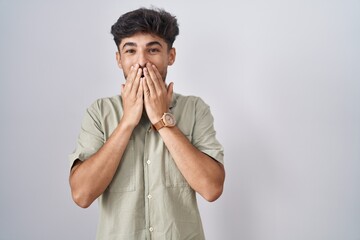 Arab man with beard standing over white background laughing and embarrassed giggle covering mouth...