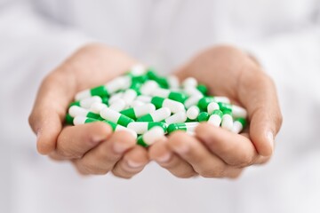 Young arab man pharmacist holding capsules at pharmacy