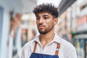 Young arab man waiter looking to the side with serious expression at street