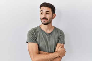 Young hispanic man with beard wearing casual t shirt over white background smiling looking to the side and staring away thinking.