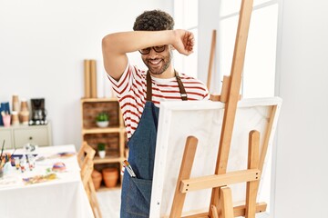 Arab young man at art studio smiling cheerful playing peek a boo with hands showing face. surprised...