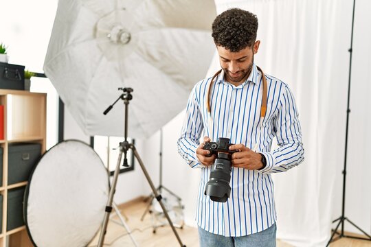 Young arab photographer man smiling happy using reflex camera at photo studio.