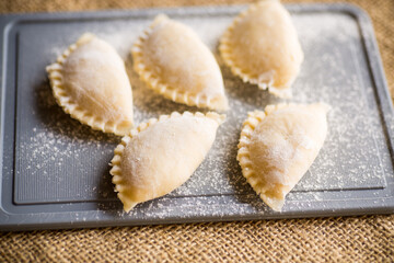 Raw dumplings . Dumplings cooking on a kitchen cutting board.