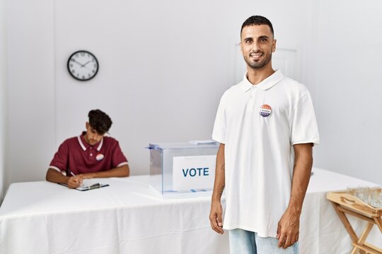 oung hispanic voter wearing vote badge standing at electoral center