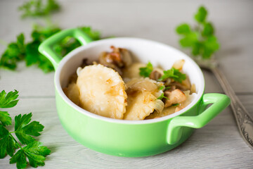Potato dumplings with onion and mushrooms in a plate.