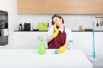 Young housewife cleaning house and talking to mobile phone at the same time