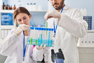 Man and woman scientist partners holding test tubes at laboratory