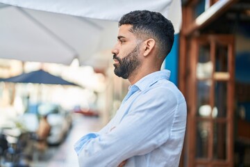 Obraz premium Young arab man looking to the side with serious expression and arms crossed gesture at street