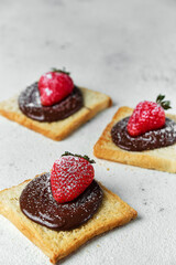 3 toasts with chocolate cream sprinkled with powdered sugar and fresh strawberries on top