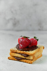 sandwich with chocolate cream sprinkled with powdered sugar and fresh strawberries on top
