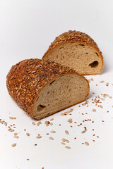 a loaf of black bread cut in half with seeds and sesame seeds on a kitchen board, top view