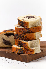 pieces of poppy seed roll on top of each other on a kitchen board on a white background front view
