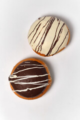 two buns with different types of cream poured with chocolate on a white background top view
