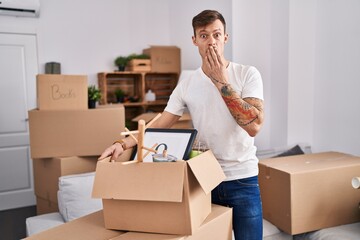 Caucasian man holding screwdriver at new home covering mouth with hand, shocked and afraid for mistake. surprised expression