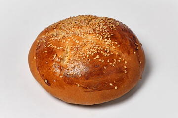 round bun sprinkled with sesame seeds on a white background close view