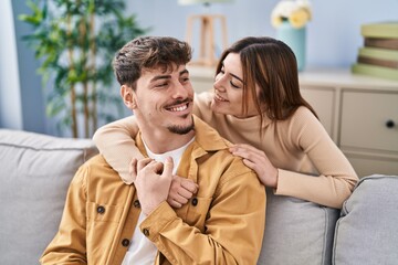 Mand and woman couple hugging each other sitting on sofa at home