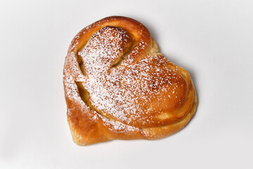 heart shaped bun with powdered sugar and vanilla cream on white background close view