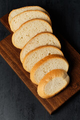 slices of white bread on a kitchen board on a black background, close view