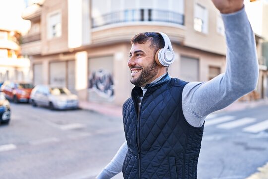 Young hispanic man smiling confident listening to music at street