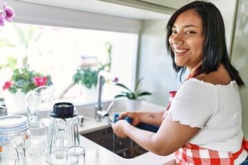 Hispanic brunette woman washing dishes at the kitchen