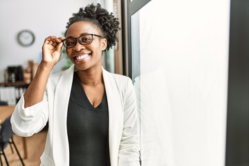 African business woman working at the office looking positive and happy standing and smiling with a...