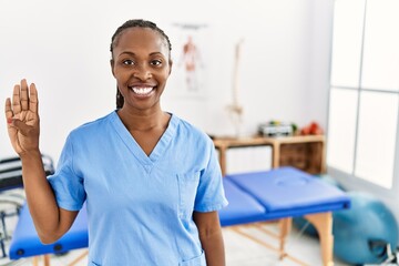 Black woman with braids working at pain recovery clinic showing and pointing up with fingers number...