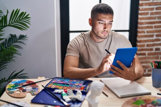 Young hispanic man artist using touchpad at art studio