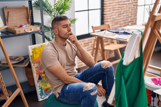 Young hispanic man looking draw with doubt expression at art studio