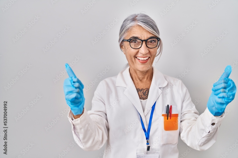 Wall mural middle age woman with grey hair wearing scientist robe success sign doing positive gesture with hand