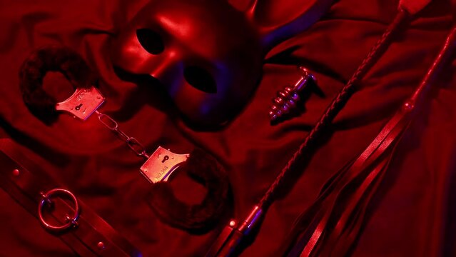 Handcuffs, leather whip flogger, mask and choker for BDSM sex with submission and domination. Concept of erotic adult sex toys