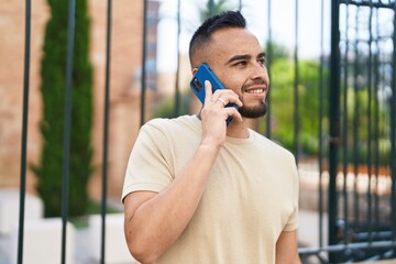 Young hispanic man smiling confident talking on the smartphone at street