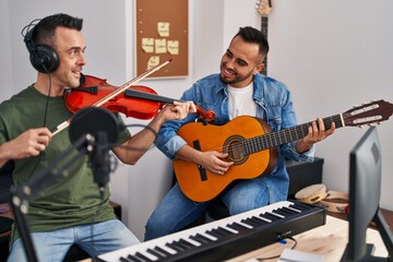 Two men musicians playing classical guitar and violin at music studio