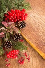 branches of holly, pine cones, mountain ash berries on wooden background