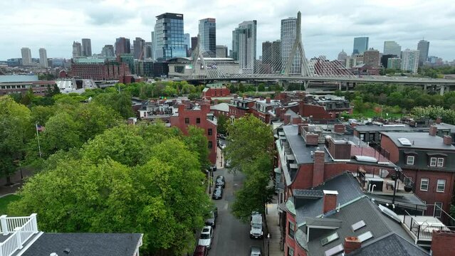 Rising aerial reveals apartment homes and houses and downtown Boston Massachusetts skyline. Zakim Bunker Hill Bridge.