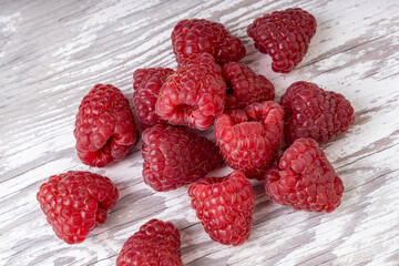 Red fresh raspberries on white wood background. Natural ripe organic berries